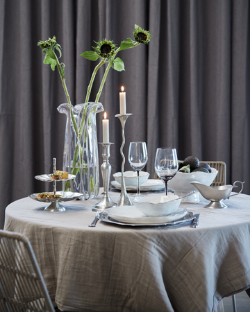 Höstbord dukat med naturkeramik, linnerservetter, levande ljus och dekorationer i varma höstfärger.