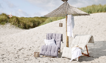 Lene Bjerres trädgårdsmöbler i stilfull design, inklusive stolar och bord, placerade i en vacker utomhusmiljö.